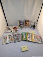 Full lot of vintage football cards displayed with some cards in protective sleeves and others stacked loosely, showing various players and teams.