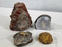 Four agate mineral specimens grouped on a white cloth background showing size range and variety of textures and colors.