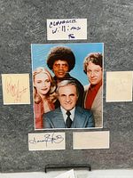 Color photo of The Mod Squad cast surrounded by five autographs mounted on gray foam core.