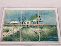 Front view of six ceramic tiles arranged in a whitewashed frame showing a coastal cottage scene with a walkway, grassy dunes, leafless tree, and boat near shore under a cloudy sky.