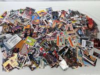 Wide view showing large pile of mixed sports trading cards spread out on a flat surface.