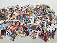 Top view of a large pile of assorted sports trading cards showing basketball and football cards mostly spread out