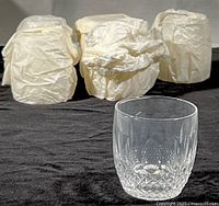 Six old fashioned glasses wrapped in original paper with one unwrapped glass in front showing the cut crystal design and size.