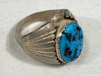 Front diagonal view showing turquoise stone and winged detailing on silver band.