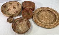 Overview photo showing six woven vintage baskets of varying sizes and shapes on a white surface