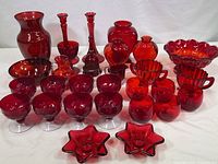 Full collection of red and amberina glassware items on white cloth background.