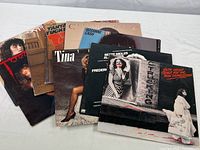 Nine vintage vinyl albums arranged overlapping on a white surface, titles and artists visible include Bette Midler, Tina Turner, Rosanne Cash, Tanya Tucker, and more.