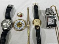 Group photo showing all four watches, gold-tone ring, and chain.