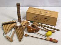 Full view of all wood percussion and flute instruments arranged on a white surface with Tapo box for scale.