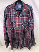 Full view of the Pendleton plaid wool shirt showing the multicolor plaid pattern in red, green, blue, and orange on a button-up shirt with two chest pockets.