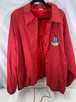 Full view of vibrant red polyester jacket on black hanger showing front and inside fleece lining.