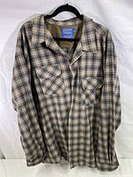 Brown, gray, and light blue plaid wool button up shirt hanging on black hanger against white background.