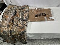 Image showing Cabelas camouflage hunting pants and Duluth Trading work shirt folded in plastic packaging