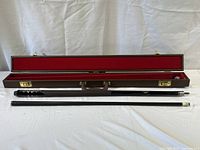 Two-piece cue and open case laid out on white backdrop