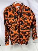 Front view of the Gander Mountain camo shirt, showing the orange and black camouflage pattern and long sleeves.