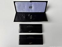 Three Montblanc booklets/manuals with white text on black covers arranged below the open case.