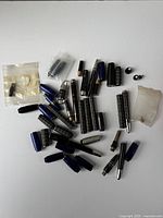 Many assorted fountain pen parts spread out on a white surface including barrels, caps, nibs, and converters.