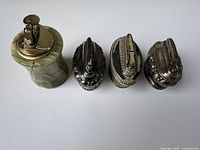 Four vintage table lighters, one green onyx base with brass top, three ornamental silver-tone metal lighters.