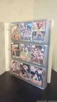 Binder open showing baseball cards in plastic sleeves, various players visible.