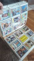 Photo of binder open showing baseball cards in standard 9-pocket plastic sleeves, featuring various players and card backs in excellent condition.