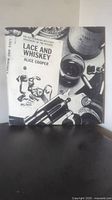 Front cover of Alice Cooper Lace and Whiskey vinyl album showing black and white photo with whiskey glass, gun, and other objects.