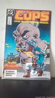 Front cover of Cops comic number 9 showing the title, cover art with a bald man firing a gun at a police officer, and publication details.
