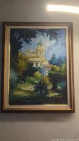 Frontal view of framed oil painting depicting a rural chapel surrounded by trees and sky.
