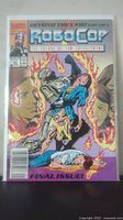 Photo of Robocop comic final issue number 23 January, cover featuring Robocop holding a woman, flames and background faces.