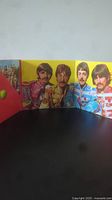 Foldout album art showing The Beatles in colorful military-style uniforms across multiple panels.
