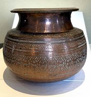 Full front view of the antique copper bowl showing its shape, wide flared rim, and etched decorative pattern.