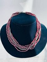 Six strand garnet bead necklace with an additional metal bead strand shown on black display bust, highlighting the twisted multi-strand design.