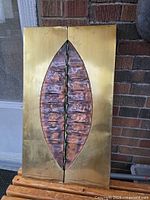 Full view of the mid-century copper and metal sculpture showing rectangular brass-framed design with central copper leaf-shaped element.