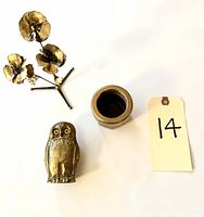 Photo showing the small brass flower bouquet, the brass owl match holder, and a round brass mechanical part, alongside a number tag for scale.