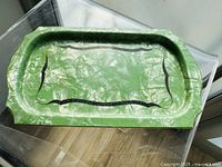Top view of vintage green marbelized celluloid serving platter with black Art Deco decorative border, showing size and shape.
