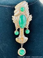 Front view of vintage Mayan carved sterling silver pendant with oval and round malachite stones attached, showing detailed carving and hanging green stones.