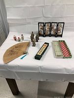 Full display of lot items including snuff bottles, terracotta soldiers, diorama screen, fan, and boxed chopsticks on white cloth-covered table.
