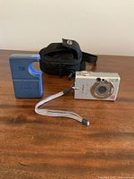 Photo showing the Canon camera, carrying case, and battery charger placed on wooden surface