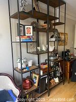 Shelf filled with various items including books, decorative objects, and bottles, showing use in a living space.