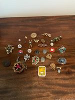 Wide shot of entire assortment of vintage pins on a wooden surface.