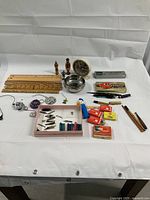 Photo showing an assortment of vintage collectibles including pens, rulers, a clock, an ashtray, small figurines, pen nibs, and ink cartridges.