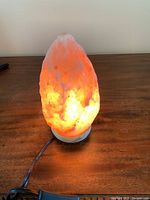 Himalayan salt lamp illuminated with warm orange glow on a wooden surface.