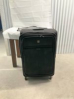 Front view of black Delsey luggage standing upright showing wheels and front compartments.