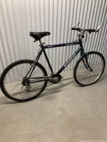 Side view of the full mountain bike with blue and purple chromoly steel frame, black saddle, flat handlebars, and knobby tires.