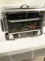 View of the front of the Black Angus Lido Oven showing glass door, chrome finish, handle, and control panel with dials.