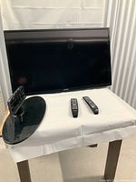 Front view of Samsung 42-inch TV with two remote controls and base stand placed on table.