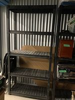 Front view of black plastic shelving unit with four vented shelves and heavy duty vertical supports.