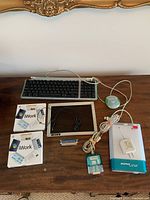 Full lot including keyboard, iWork CDs, SuperDisk, screen, mouse, cables, and adapter laid out on wood table.