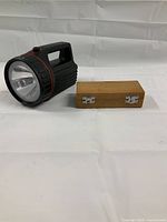 Vintage black Lee Valley flashlight next to a closed wooden box with metal clasps