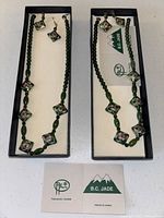 Two sets of green B.C. Jade necklaces and earrings new in box, showing floral diamond-shaped beads and jade bead detail