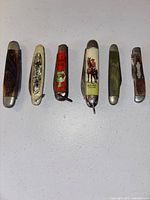Front view of all six vintage pocket cutters in a row showing handle designs and condition